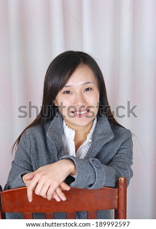 Portrait of smiling woman resting chairs on hand.