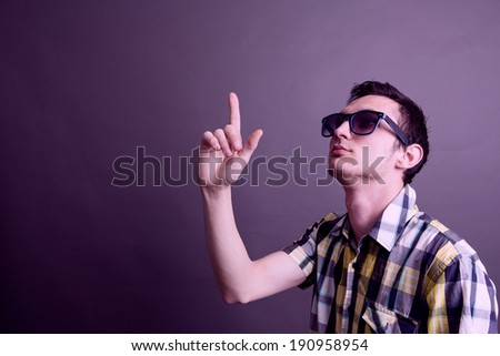 A guy wearing sunglasses pointing with his finger up