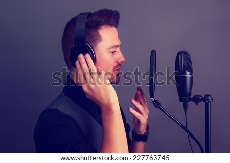 Guy singing at a microphone wearing headphones