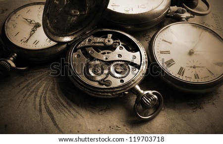 Antique pocket watch on old photos back, sepia