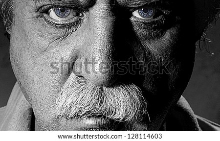 Closeup black and white character portrait of a man with blue eyes looking at the camera with questioning and suspicious facial expression
