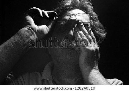 tired middle-aged man rubs his eyes< black and white