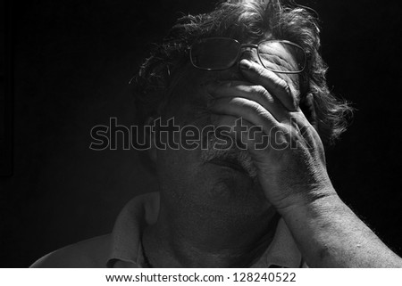 tired middle-aged man rubs his eyes< black and white