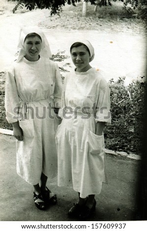 VOROSHILOVGRAD, UKRAINE - CIRCA 1957: Two young nurses in white gowns posing in the yard Regional Cancer Center, Voroshilovgrad, now Lugansk, Ukraine, USSR, 1957