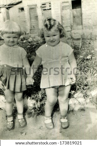 GERMANY - 1950s: An antique photo shows two little girls holding hands, standing in the yard