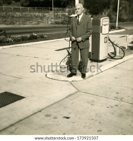 GERMANY, PFALTZ -  September, 1964: An antique photo shows man in suit and tie standing near the column at a gas station