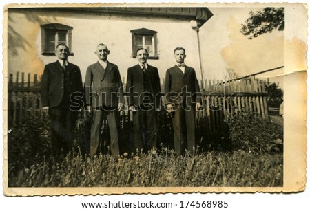 GERMANY -  CIRCA 1930s: An antique photo shows four men in formal suits standing in front of house