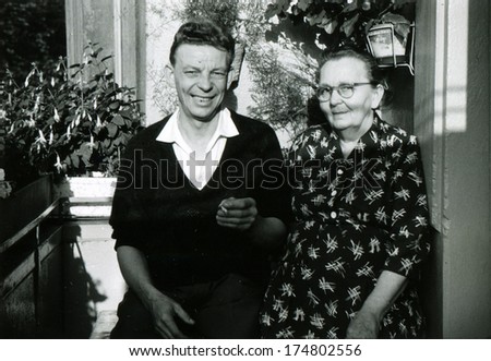 GERMANY -  CIRCA 1960s: An antique photo shows old woman and man with cigarette posing on the balckony