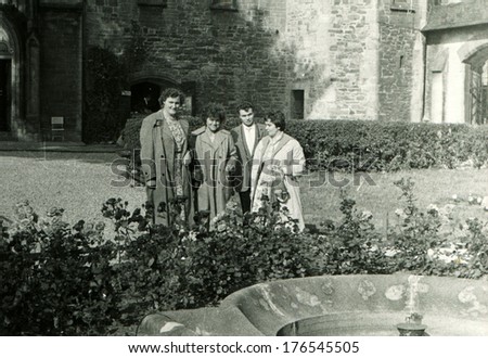 GERMANY, RHEINEBARG - CIRCA 1950s: An antique photo of three women and one man standing near the fountain in the courtyard of an ancient fortress