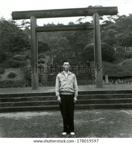 JAPAN  - 1950s: An antique photo shows young man on a background of the temple gate. Sacred gate, Torii (\
