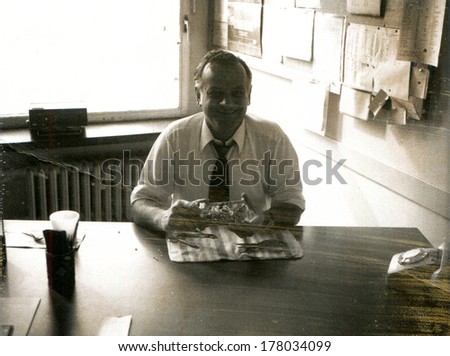 GERMANY -  1960s: An antique photo shows man in white shirt and tie sitting at a table with his back to the window