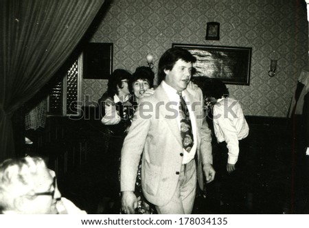 GERMANY -  CIRCA 1960s: An antique photo shows man in a light suit is against the background of dancing women in a restaurant