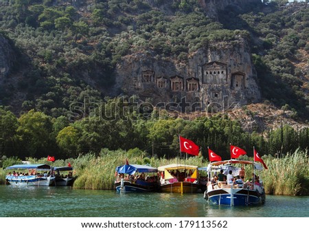 TURKEY, DALYAN, MUGLA - JULY 19, 2013: Pleasure boat with tourists in the mouth of the Dalyan River under Lycian tombs