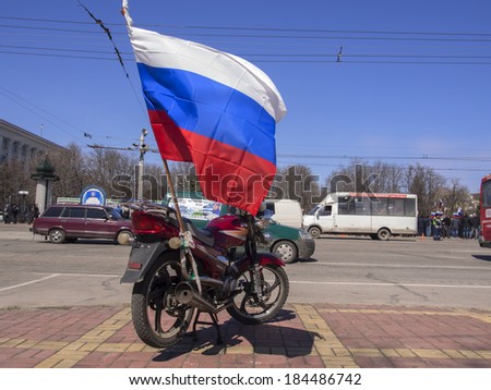 LUGANSK, UKRAINE - MARCH 30, 2014: bike with a fixed to it a Russian flag on the background of the rally.  Lugansk separatist rally gathered only about 500 people.