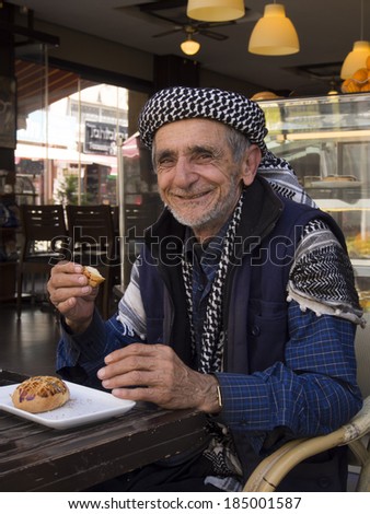 TURKEY, MARMARIS - April 26, 2013: elderly man in traditional headscarf eating bun at the table restaurant