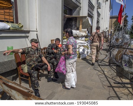 LUHANSK, UKRAINE  - May 16, 2014: Armed separatists guarding captured them Lugansk regional administration, offer employee Department of Justice to pass on another way to get to her job.