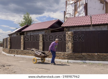 MAKAROVO, LUHANSK REGIPN, UKRAINE - June 13, 2014: An elderly man carries home on the trolley planks of Restaurant \