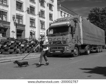 LUHANSK, UKRAINE - June 20. 2014: Woman with a dachshund on a leash goes past the truck parked near the entrance to Luhansk regional administration, controlled by separatists