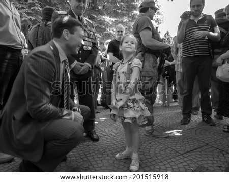 LUHANSK, UKRAINE - June 29, 2014: The  the self-proclaimed parliament of Novorossia speaker Oleg Tsarev talking to a little girl, watching them elderly man in uniform with numerous awards on jacket