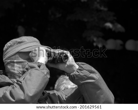 LUHANSK, UKRAINE - June 29, 2014: Armed man of private security company looking to the binicular