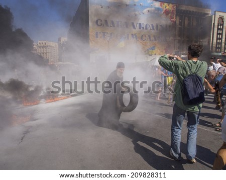 KYIV, UKRAINE - Aug 7, 2014: A priest with a tire in the hands near the barricades. -- Activists and police have clashed in Ukrainian capital\'s center after communal workers tried to dismantle camp