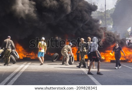 KYIV, UKRAINE - Aug 7, 2014: Activists throw tires in the fire. -- Activists and police have clashed in the Ukrainian capital's center after communal workers tried to dismantle the camp.