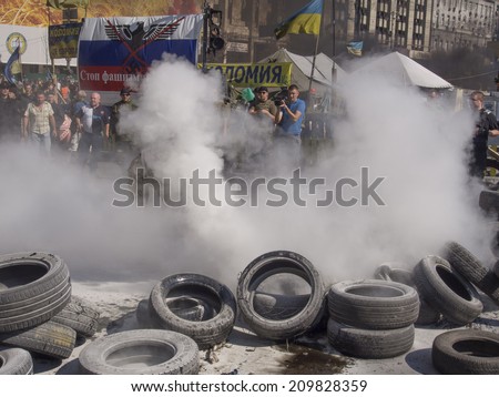 KYIV, UKRAINE - Aug 7, 2014: Activists throw tires in the fire. -- Activists and police have clashed in the Ukrainian capital\'s center after communal workers tried to dismantle the camp.