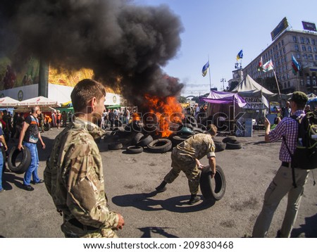 KYIV, UKRAINE - Aug 7, 2014: Activists throw tires in the fire. -- Activists and police have clashed in the Ukrainian capitals center after communal workers tried to dismantle the camp.