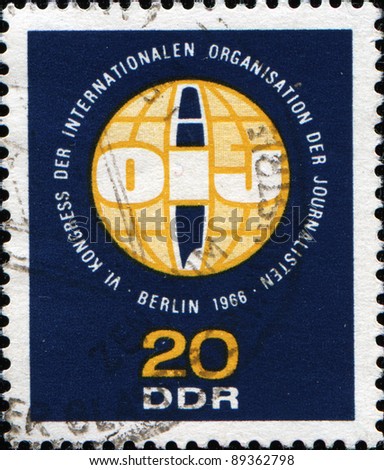 GDR - CIRCA 1966: A stamp printed in Germany shows The International Organization of Journalists logo, circa 1966