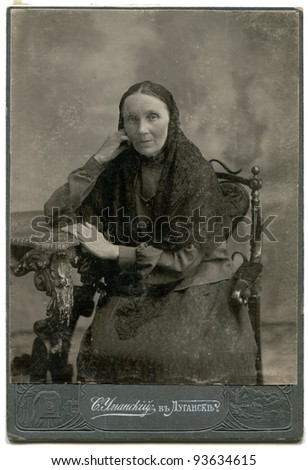 RUSSIA - CIRCA end of XIX - beginning of XX century: An antique photo shows elderly woman sitting in chair near the table, Lugansk, Russia, now Ukraine Russian text: Umanskiy (name of photographer), L
