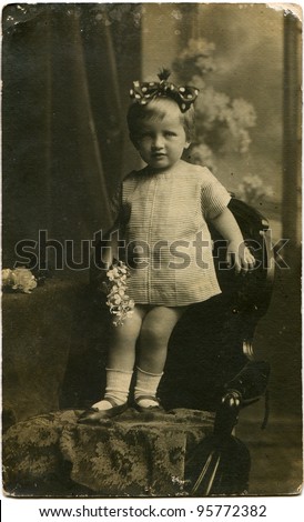RUSSIAN EMPIRE - CIRCA beginning of the 20th century: little girl in a striped dress with a bow on her head standing on a chair, circa the beginning of the 20th century