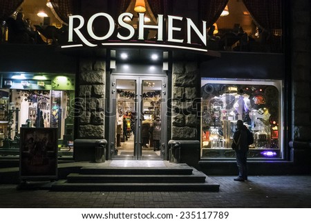KIEV, UKRAINE - December 3, 2014: Man sees a brightly lit shop window corporate store Rochen on Khreschatyk Street in heart of Kiev, Ukraine. Business owned by president of Ukraine Petro Poroshenko