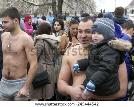 KIEV, UKRAINE - January 18, 2015: Ukrainian Church of the Moscow Patriarchate traditionally celebrated Epiphany in Obolon. A man who is going to bathe in river, holding little boy in winter clothes.