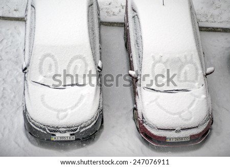 KIEV, UKRAINE - January 22, 2015: Funny faces drawn on the snow on the windshield of the car parked in the courtyard of a condo. In Ukraine is rainy-snowy day.
