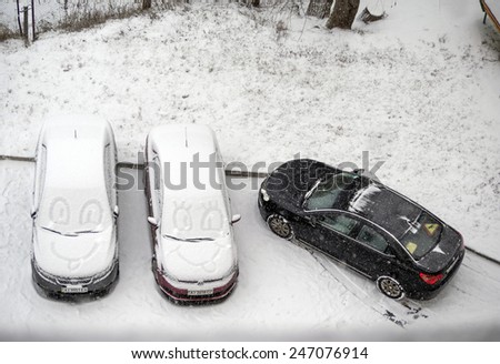 KIEV, UKRAINE - January 22, 2015: Funny faces drawn on the snow on the windshield of the car parked in the courtyard of a condo. In Ukraine is rainy-snowy day.
