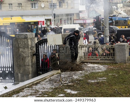 KIEV, UKRAINE - February 2, 2015: Deputy chief of police of Kiev climbs over the fence of the Ministry of Defence of Ukraine, as the entrance is blocked by protesters.