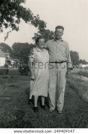CANADA - CIRCA 1940s: Reproduction of an antique photo shows farmer\'s family posing in the garden near his home