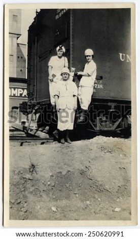 CANADA - CIRCA 1930s: Reproduction of an antique photo shows Three women in white summer dress posing near the freight car