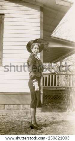 CANADA - CIRCA 1950s: Reproduction of an antique photo shows elegant woman in gloves and hat posing against the backdrop of a private house