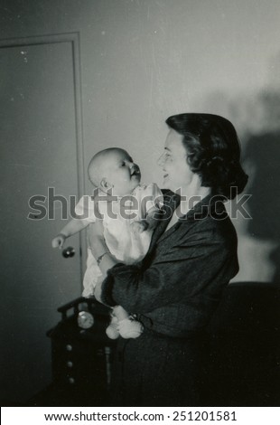 CANADA - CIRCA 1950s: Reproduction of an antique photo shows woman nursing a baby in her arms