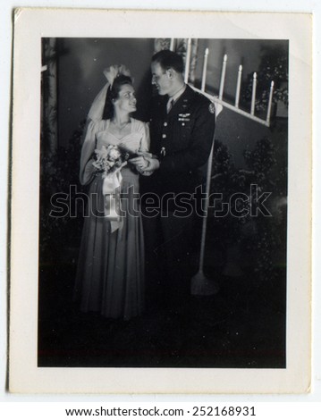 CANADA - CIRCA 1940s: Reproduction of an antique photo shows Bride and groom posing in the synagogue on the background of a menorah, the groom is a military pilot of the US Air Force