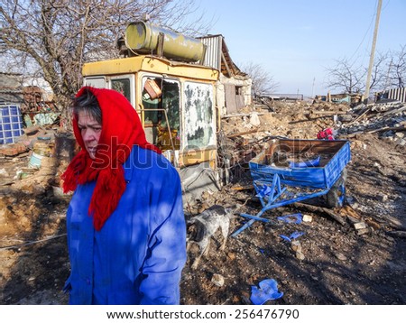 NIKISINO, UKRAINE - Feb 27, 2015: A woman walks past a destroyed house. Village Nikishino located 20 km from Debaltseve, Ukrainian military was abandoned three days ago.
