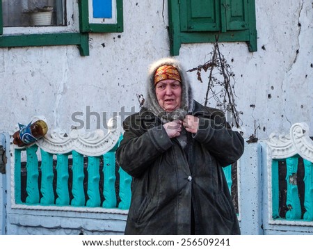 NIKISINO, UKRAINE - Feb 27, 2015: Middle-aged women stay near her ruined house in the village Nikishino, Donetsk region, Ukraine. - Village Nikishino located 20 km from Debaltseve,