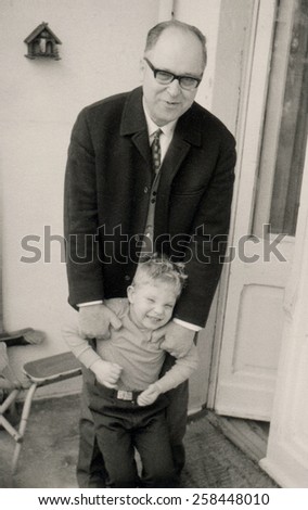 GERMANY - CIRCA may, 1970: Bald middle-aged man in a business suit posing with a little boy