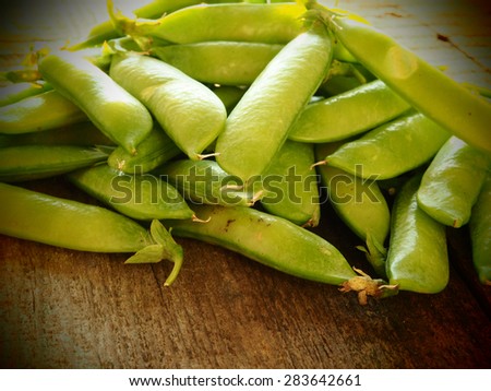 Freshly picked snow peas on a rustic board. Grungy style.