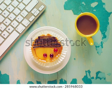 Computer keyboard, cup of coffee and  cake on blue painted weathering table. Grunge style