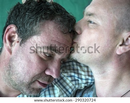 Caucasian man kissing another man in the forehead