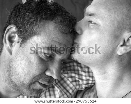 Caucasian man kissing another man in the forehead