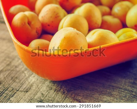 Fresh apricots in orange bowl on wooden weathering table. Grunge style