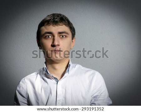 young man in a light shirt with open collar. surprised